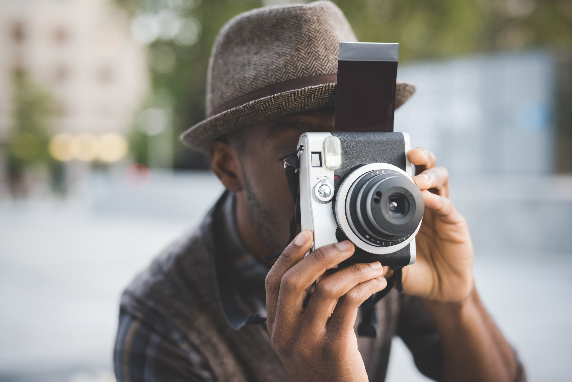 Half length of young beautiful afro black man outdoor in the city holding instant camera, shooting - photography, creative, artist concept